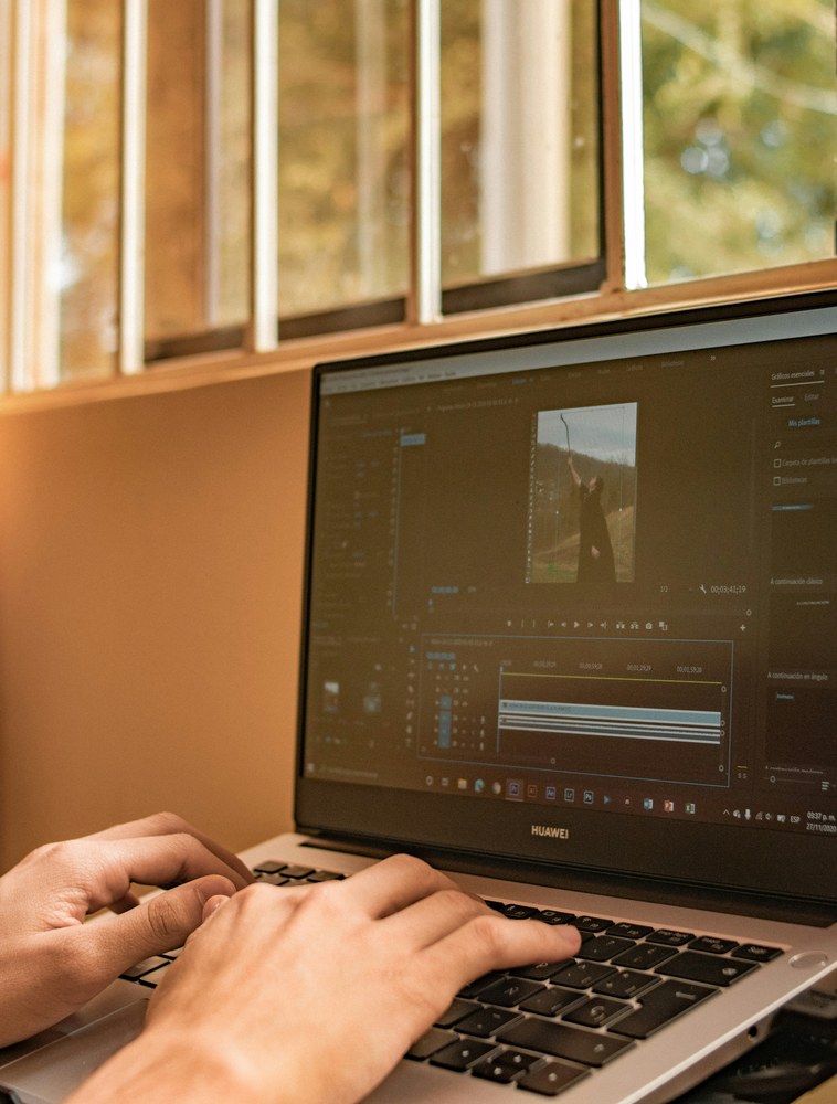 Editor at work on a laptop, editing timeline visible